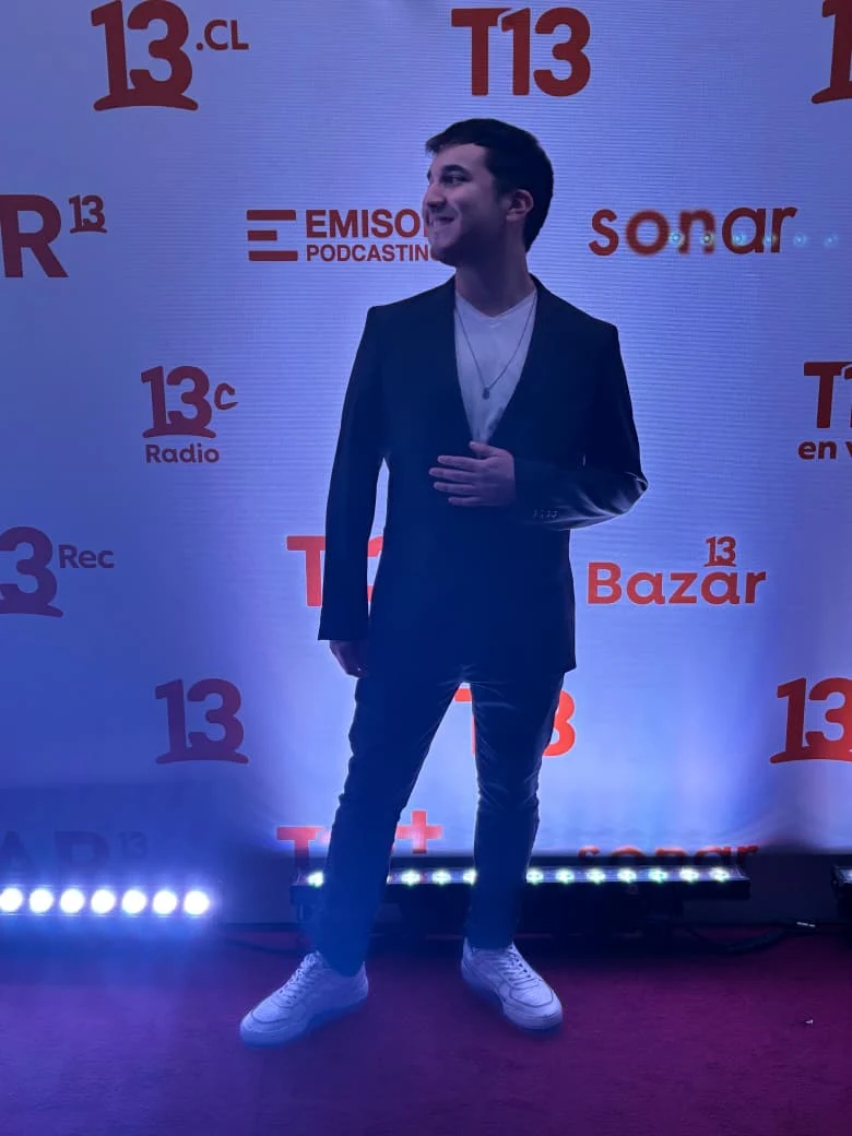 Lucas in front of the Canal 13 brand wall at Expo 13 Fest